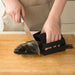 Person cutting a whole fish on a wooden cutting board using a knife, while securing the fish with a black silicone fish holder featuring a non-slip grip. The user is wearing a beige apron, and the scene is set in a kitchen environment—demonstrating safe, stable, and efficient fish preparation for cooking.- 1598452898401 13017586
