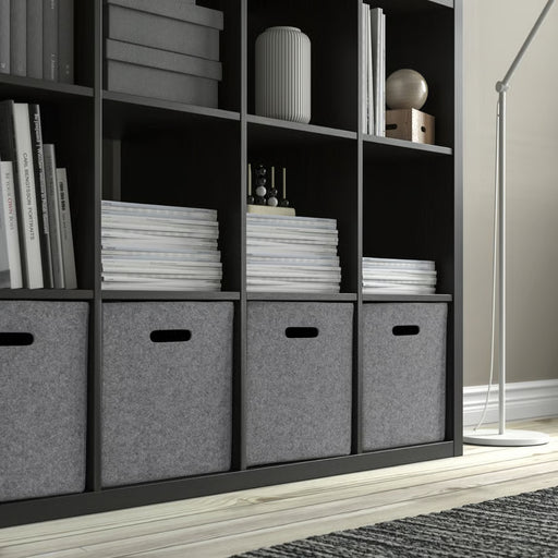 Bookshelf with books and gray storage boxes in a room setting