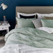 Bedroom with a bed featuring green bedding and pillows against a blue wall.