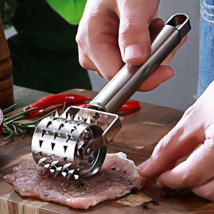 Person using a meat tenderizer on a piece of meat with a wooden cutting board in the background.