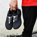 Digital Shoppy Person holding black athletic shoes with white elastic no-tie laces and central lock