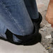 Digital Shoppy Sports Knee Pads – Close-up of black knee pads with hard shell worn over jeans for construction work