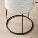 Close-up of IKEA STRANDAD floor lamp base with black metal frame and circular stand; white paper shade with horizontal ridges on wooden floor – 50594838