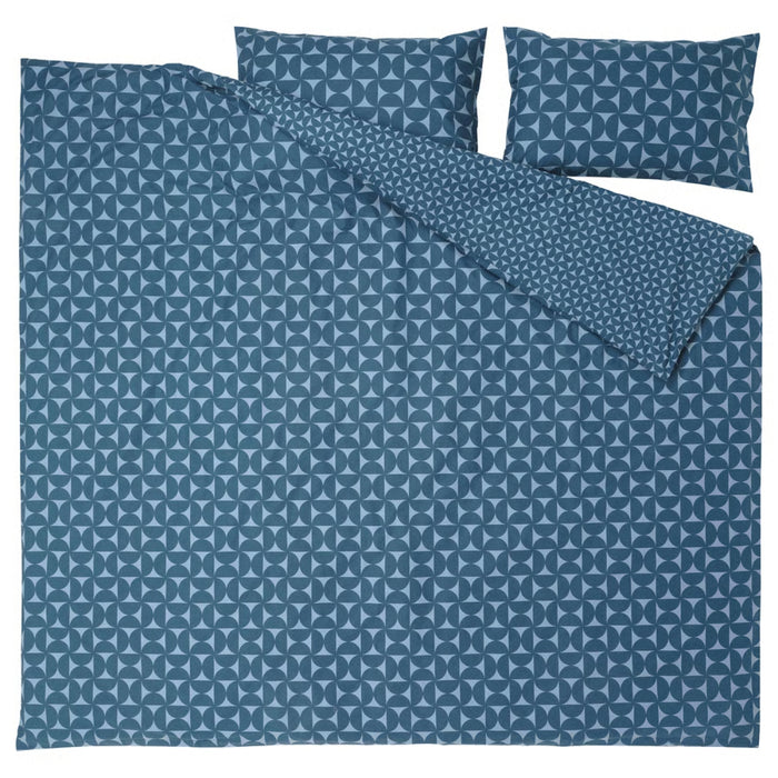 IKEA ÄNGSNEJLIKA duvet cover partially folded back to reveal reversible design: one side with large circular blue motifs, the reverse with smaller, densely packed geometric shapes in similar tones.