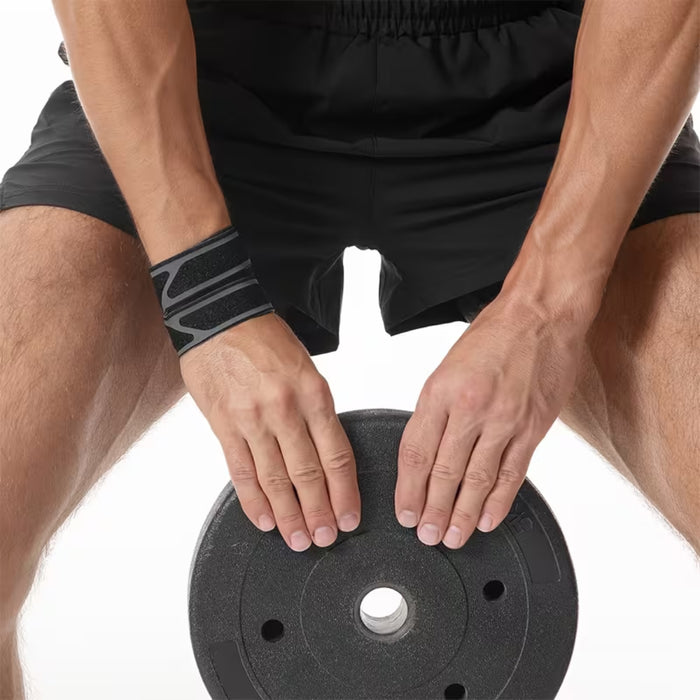 Athlete using the breathable wrist support while handling a heavy gym weight plate for joint protection.