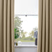 Beige curtains with a window in the background showing greenery