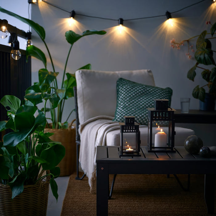 Outdoor evening setting with a cozy chair, lanterns, and candles on a table.