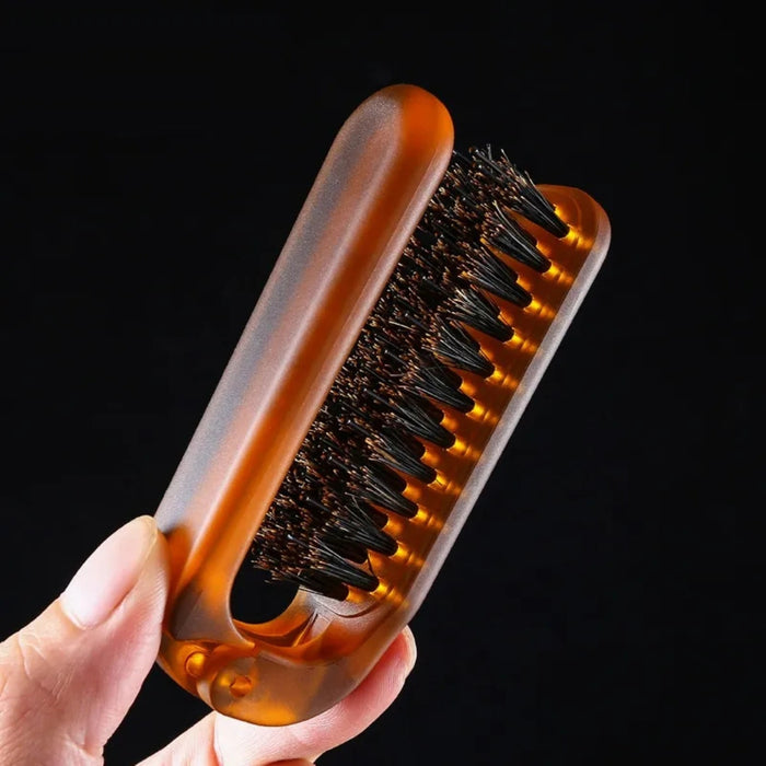 Hand holding a brown brush with black bristles against a black background