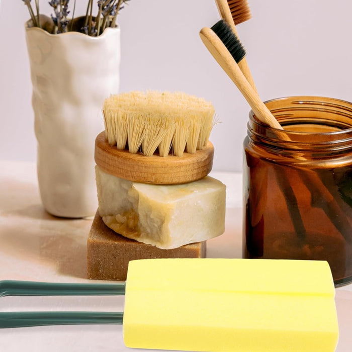 Yellow sponge brush with green handle placed among bamboo toothbrushes, handmade soaps, and natural bristle brushes – part of sustainable hygiene kit – 1598453485864 13972338