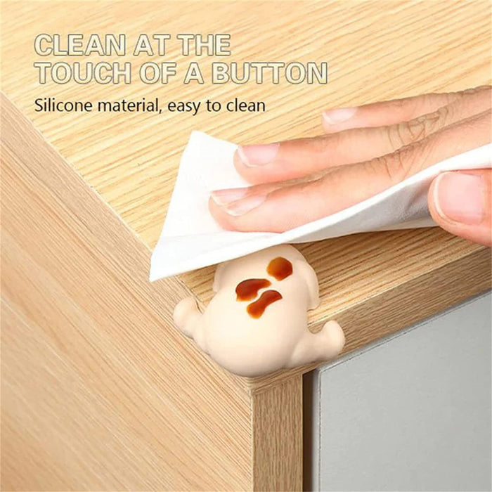 Soft silicone corner protector shaped like a cartoon puppy, attached to a wooden surface. Easy to clean and ideal for childproofing furniture edges. Pack of 4.-