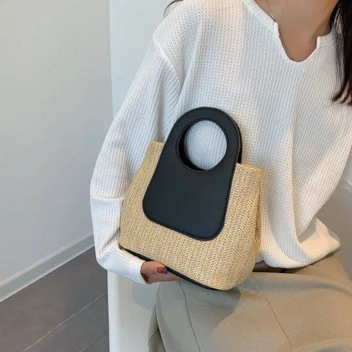 Digital Shoppy Seated person in white top and beige pants holding retro straw bag with black cut-out handle