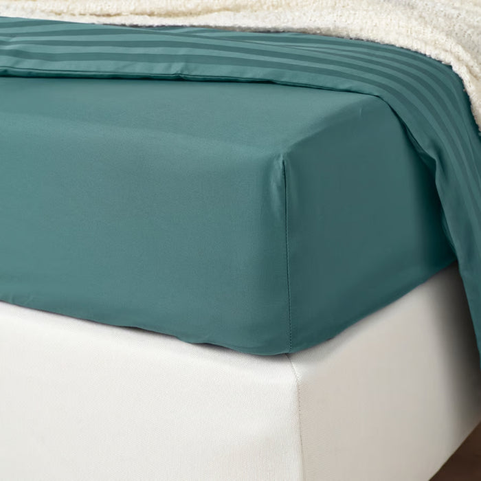 Teal bed sheet on a white bed
