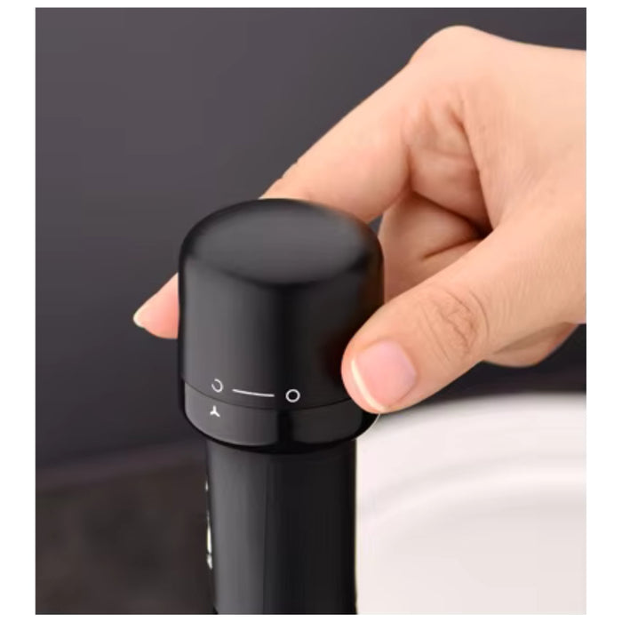 A close-up of a hand holding a black bottle stopper on a dark background.