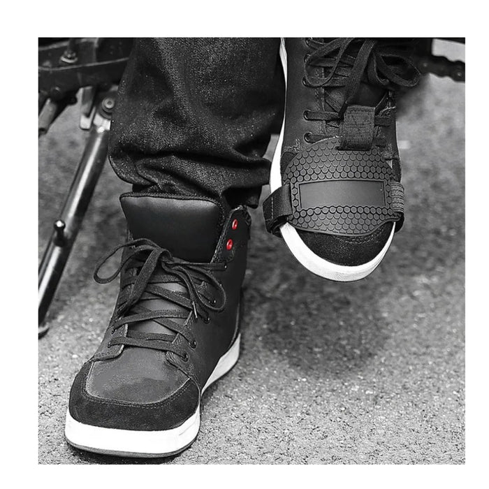 Black high-top sneakers with white soles worn by a person on a textured surface.