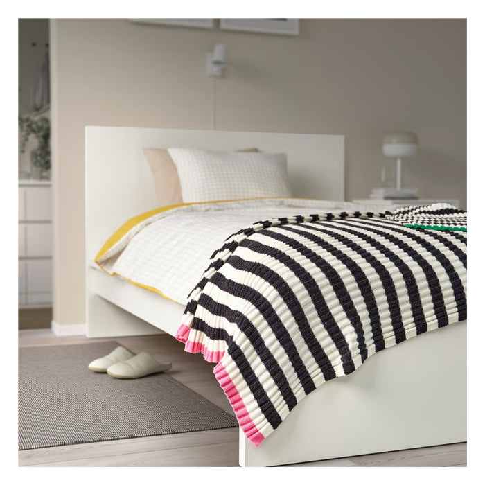 Bed with striped blanket in a bedroom setting