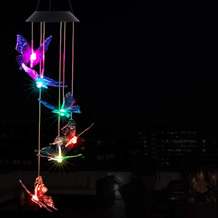Hanging solar-powered LED wind chime featuring butterfly-shaped lights glowing in vibrant colors—purple, blue, green, red, and yellow—against a nighttime outdoor backdrop. Perfect for garden, patio, or yard decoration, enhancing ambiance with color-changing illumination.