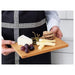 Person holding a wooden cheese board with cheese, grapes, and crackers.