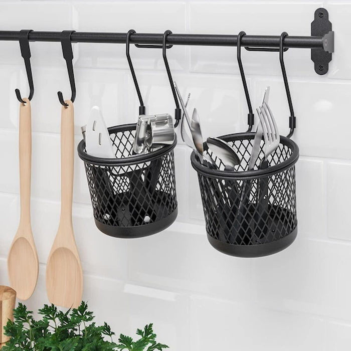 Black hanging baskets with utensils on a kitchen wall