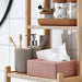 Bathroom shelf with various items including a tissue box, soap dispenser, and toothbrush holder.