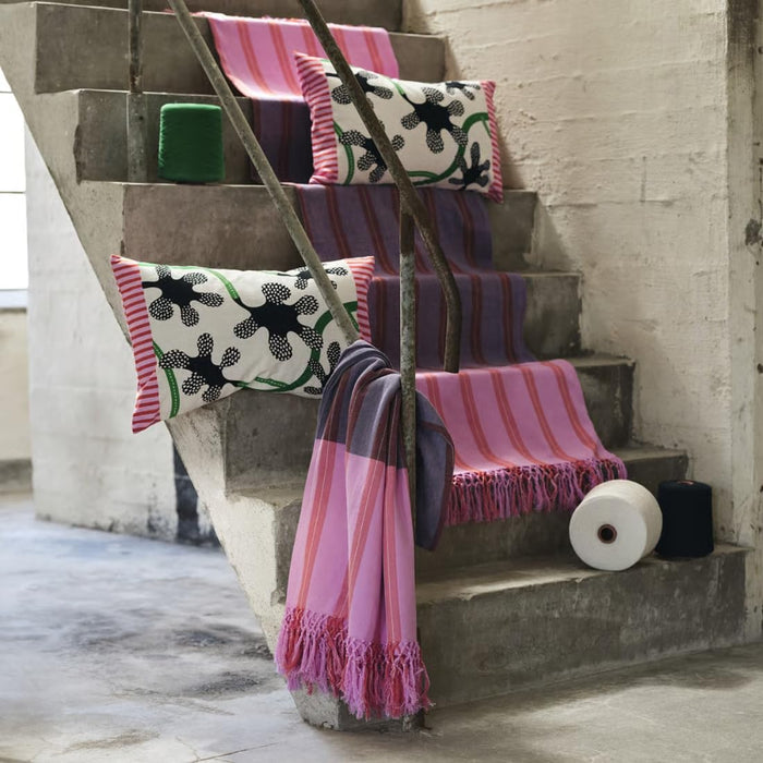  Concrete staircase decorated with MÄVINN throws in pink and purple tones, paired with floral cushions and yarn spools