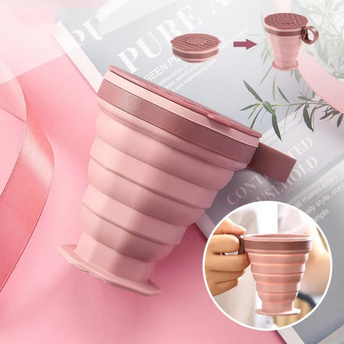 Collapsible pink silicone cup with handle on a pink background