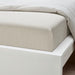 Neatly made bed with IKEA SOLFIBBLA white beige striped fitted sheet on white bed frame