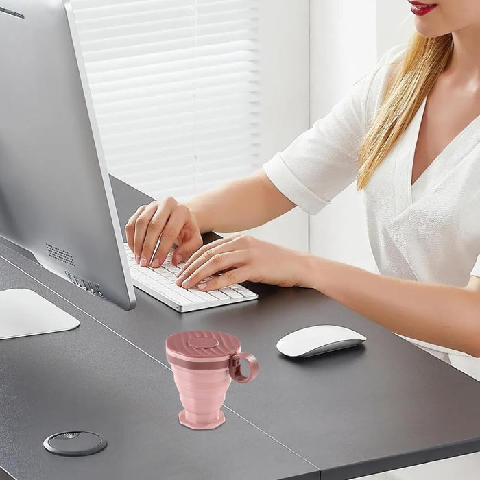 Person using a computer with a pink mug on a desk