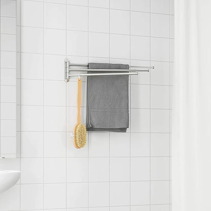 Towel rack with a gray towel and a gold brush on a white tiled bathroom wall.