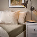 Cosy bedroom styled with IKEA ULLVIDE grey-beige fitted sheet beige pillows and warm lighting