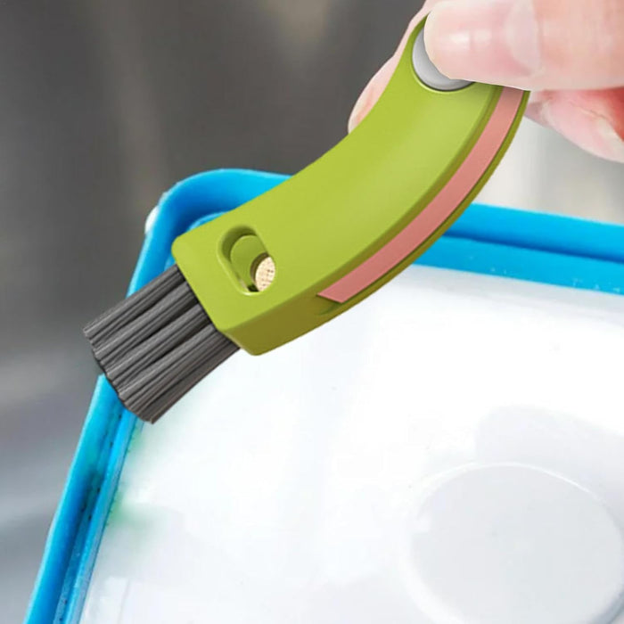 Green and pink brush with bristles being used on a white surface.