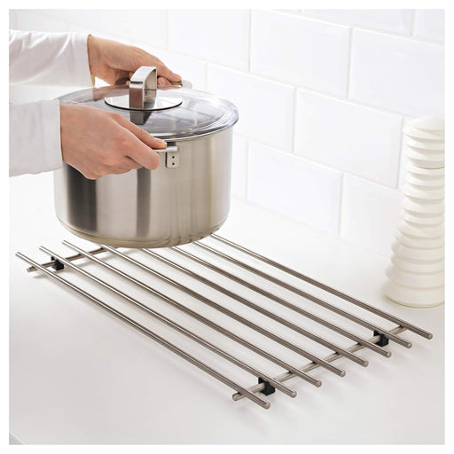 Person lifting a pot with a lid over a metal rack on a white tiled wall background