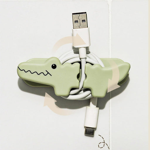 Green alligator-shaped cable organizer with USB and Lightning cables on a white background