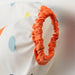 Orange scrunchie on a white background with colorful polka dots