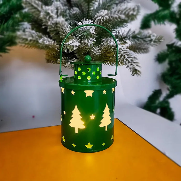 Green lantern with tree and star patterns on a wooden surface with a blurred Christmas tree in the background.