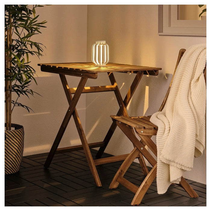 Wooden folding table and chair set on a deck with a candle lantern.