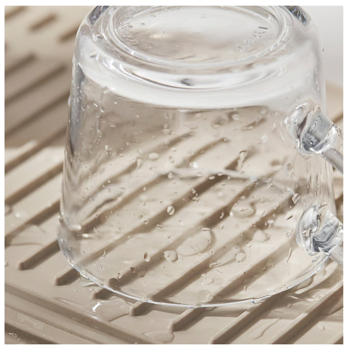 Clear glass teapot with water droplets on a textured surface
