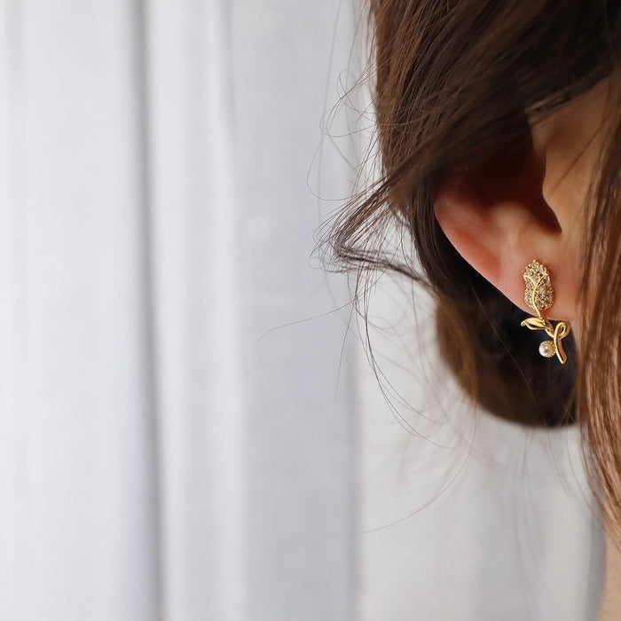 Gold earring worn by a person with a white background