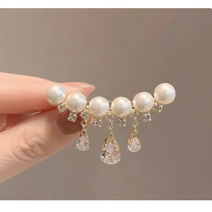 Pearl hair clip with crystals held by a hand against a neutral background