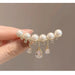 Pearl hair clip with crystals held by a hand against a neutral background