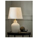 
Elegant ceramic table lamp with beige shade, styled on a black side table alongside books, eyeglasses, and a decorative sphere in a cozy living space.


