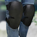 Digital Shoppy Sports Knee Pads – Black knee pads strapped over jeans while kneeling on rough concrete surface