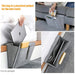 Gray bed caddy with compartments holding a laptop, books, and other items on a bed.