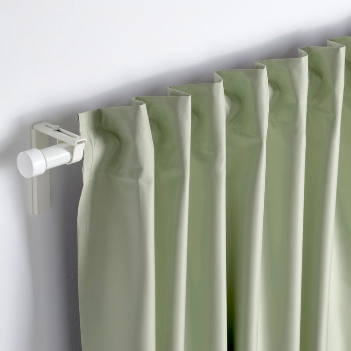 BENGTA block-out curtain, green, 210x250 cm. Pleated panel hung on white rod with cylindrical finial and wall bracket – soft fabric blocks light elegantly – 60602164.
