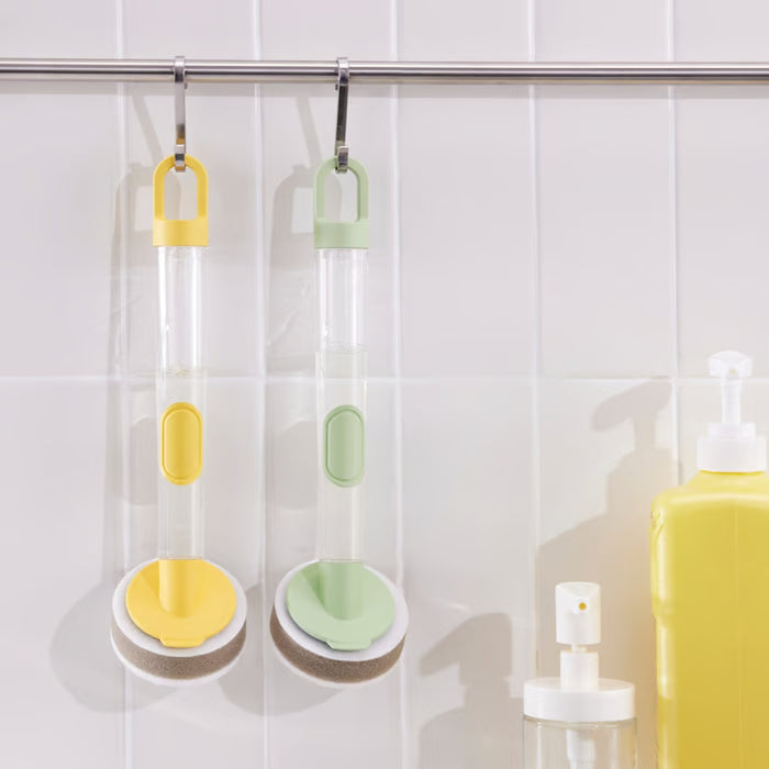 This image showcases two VIDEVECKMAL dish sponge dispensers, one in light green and another in a cheerful yellow, both conveniently hung from a rail on the wall. This design allows for quick drying and easy access. Each dispenser comes with an attached sponge, ready to tackle your dishwashing needs.