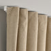 Close-up of beige curtains hanging on a rod against a gray wall.