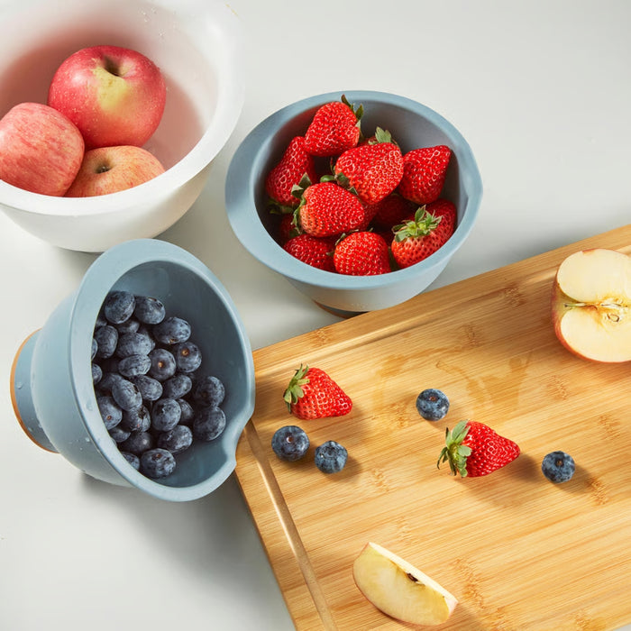 A selection of fresh fruits arranged in bowls and on a wooden cutting board, featuring apples, strawberries, and blueberries. The vibrant colors and natural textures create a visually appealing food presentation.- 90607438