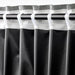 Black curtains with gray trim on a rod against a white background