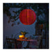 Red paper lantern hanging above a table with candles and plants in an outdoor setting.