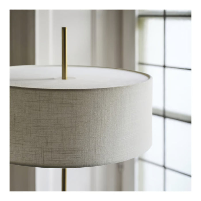 Close-up of a lamp with a white shade and metallic base against a window background.