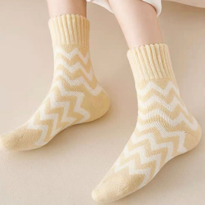 Feet wearing mango yellow zigzag socks resting on light surface with rolled-up white pants
